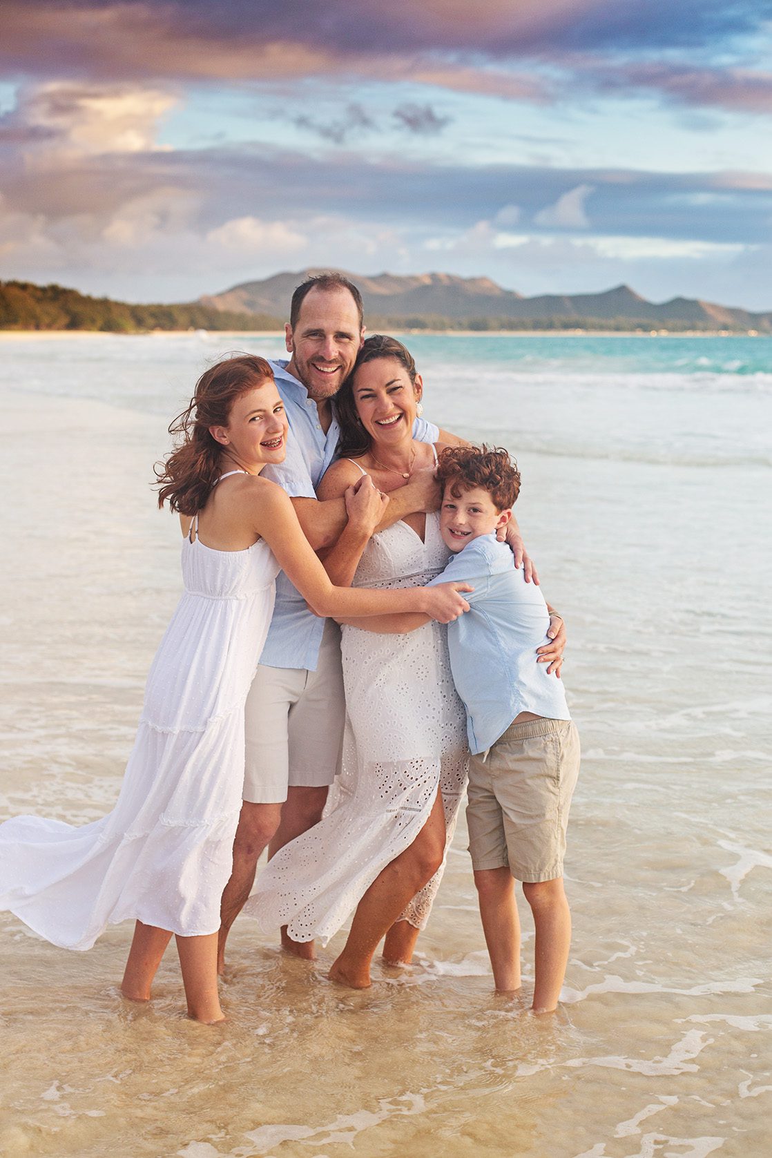 family hugging in the ocean during photo session on oahu