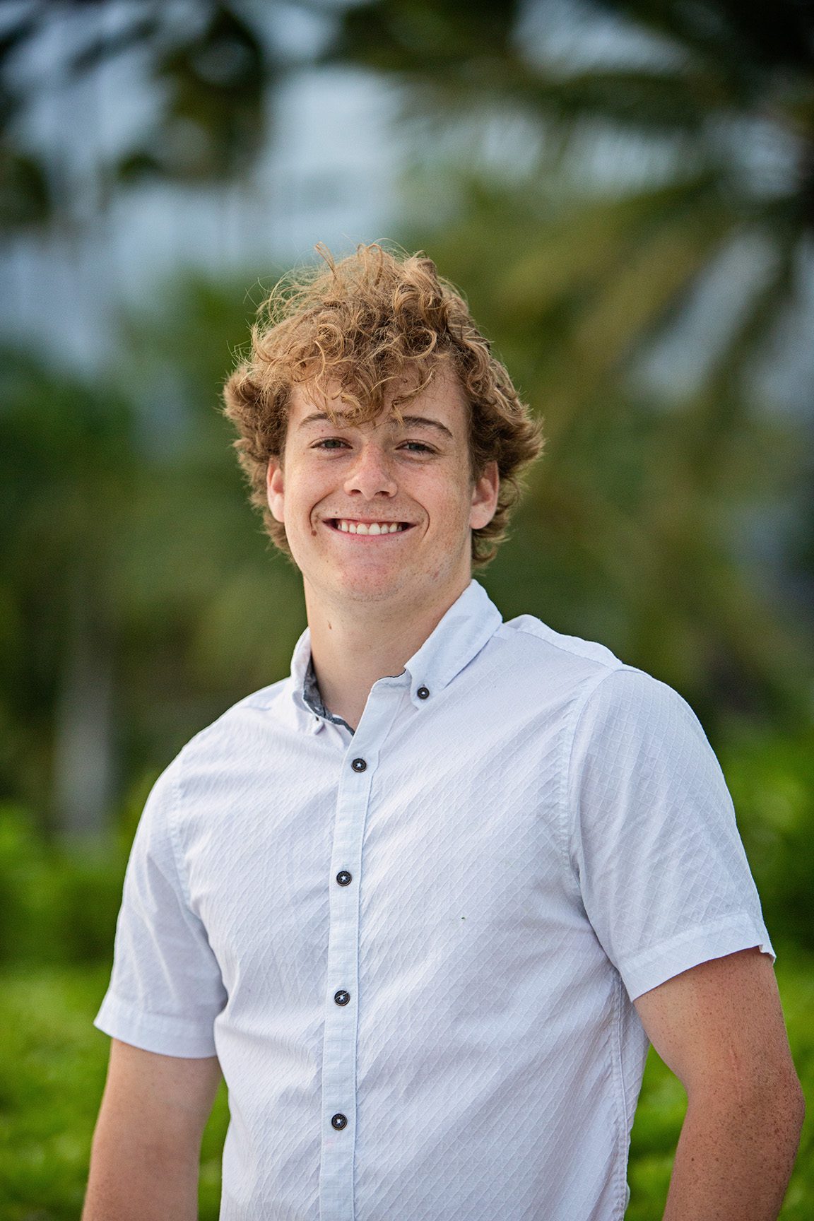 boy senior portrait on beach in Hawaii with palm trees