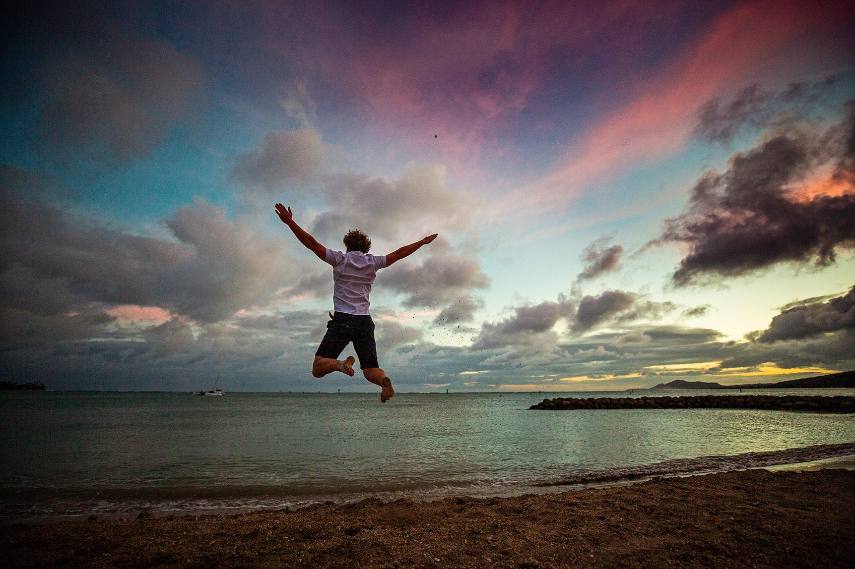 boy senior portrait on beach in Hawaii at sunset, jumping