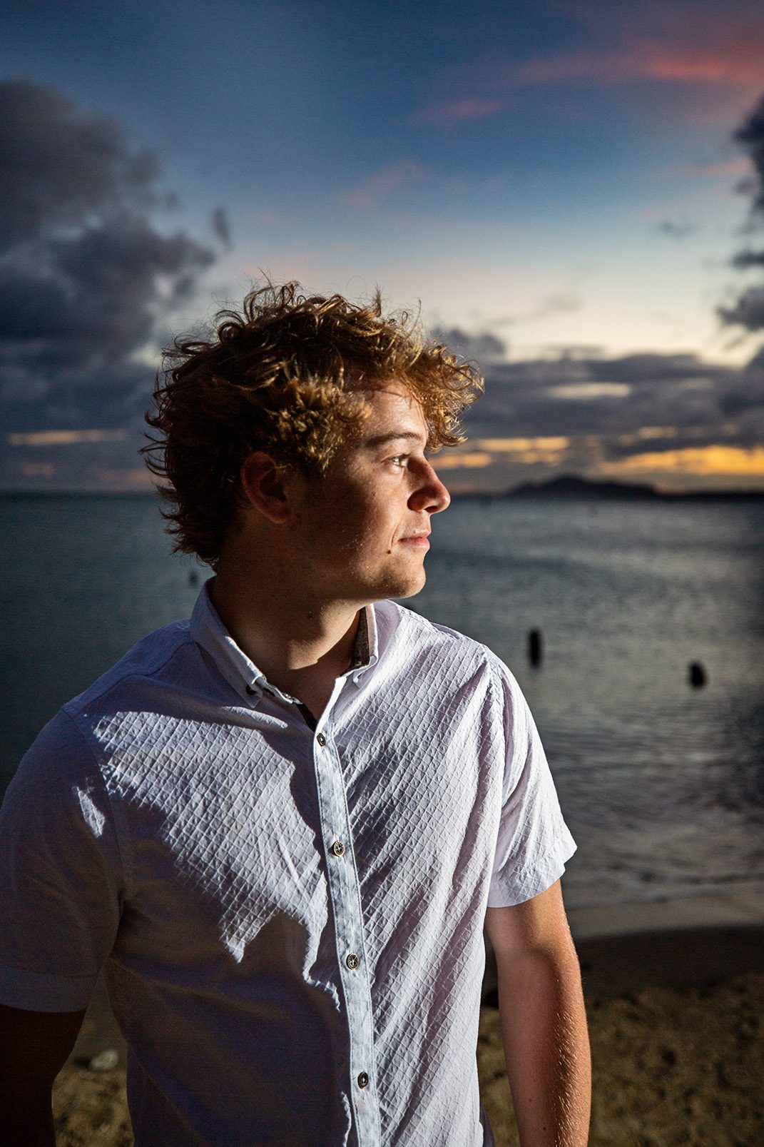 boy senior portrait on beach in Hawaii at sunset