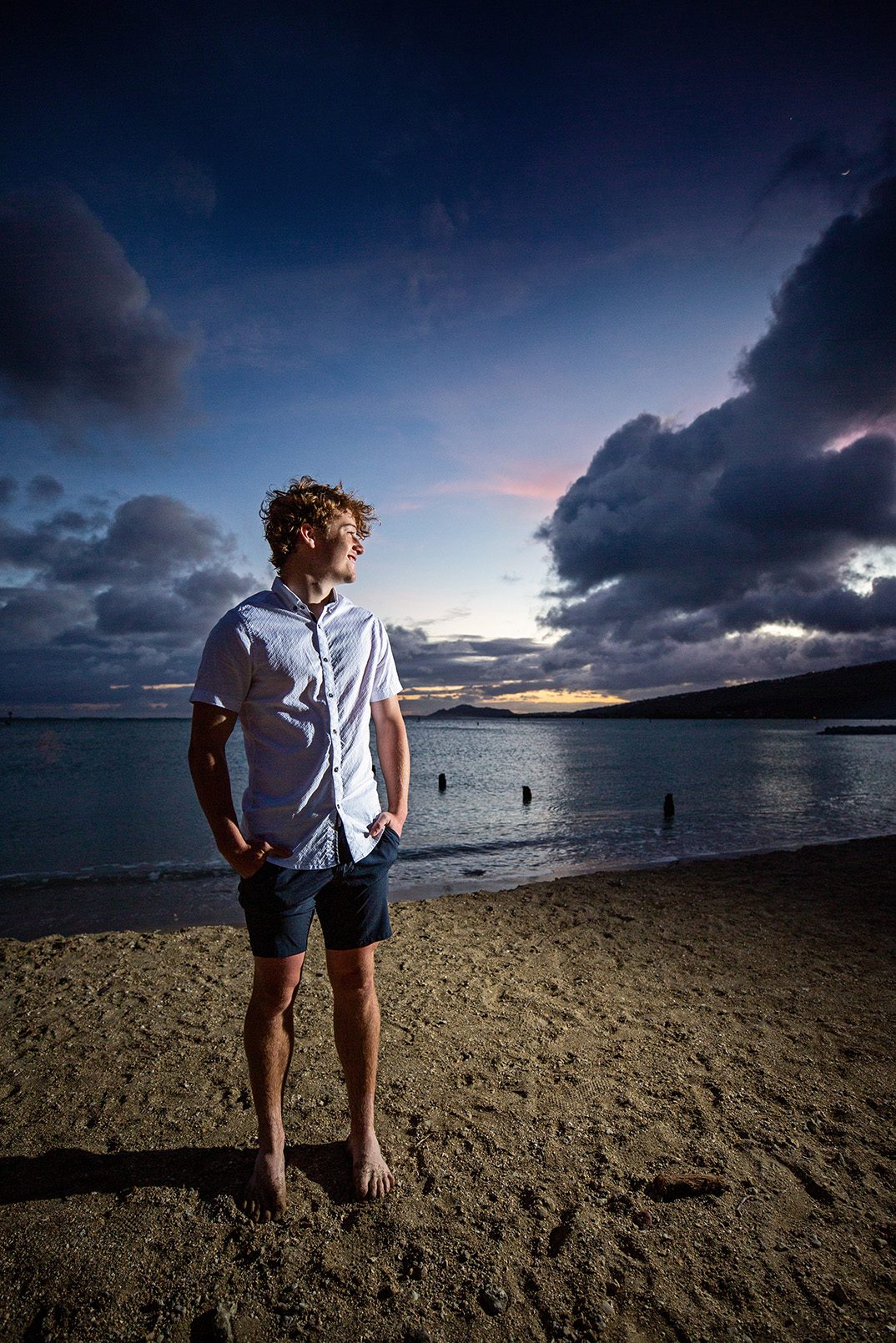 boy senior portrait on beach in Hawaii at sunset