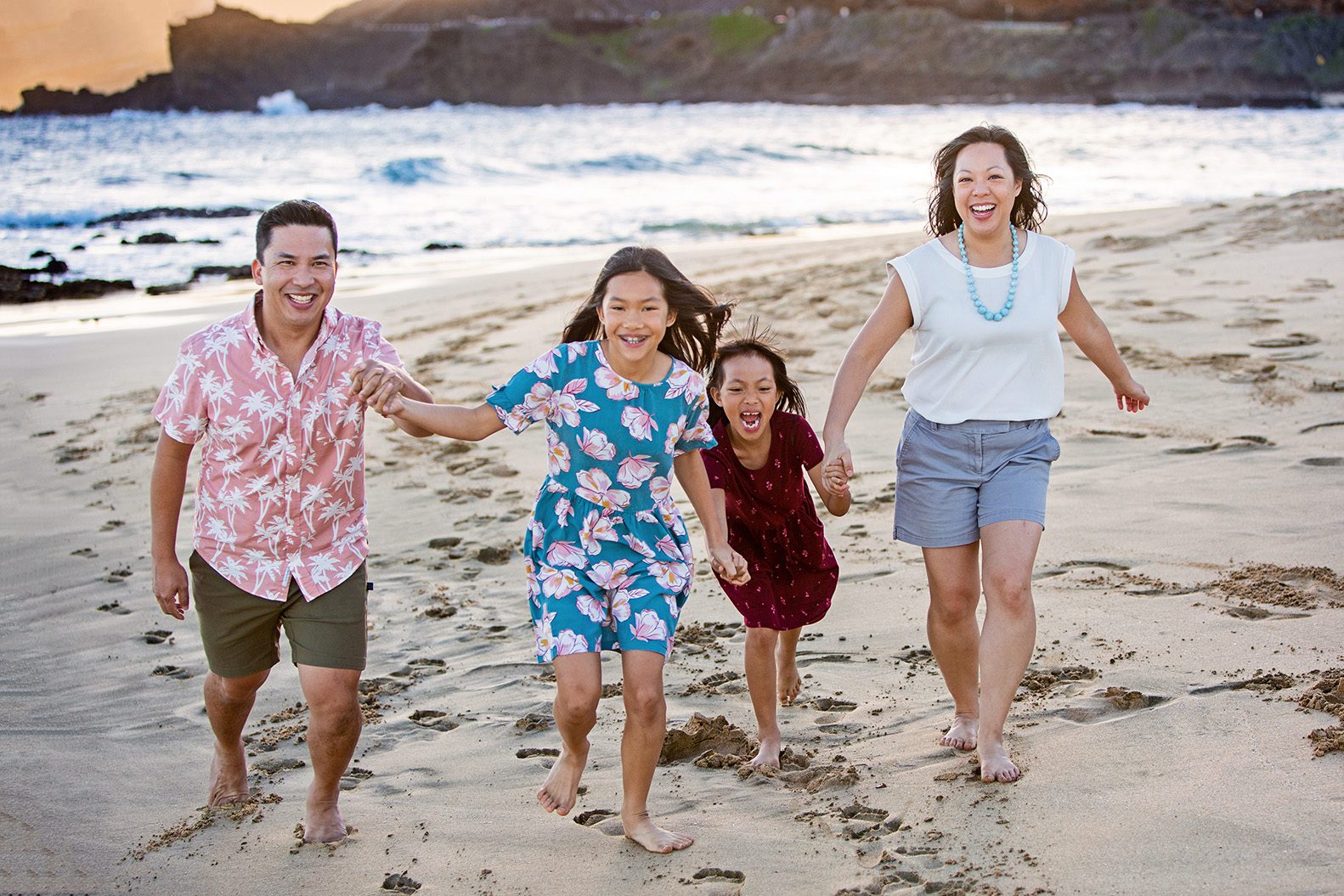 playful family runs on beach in Hawaii
